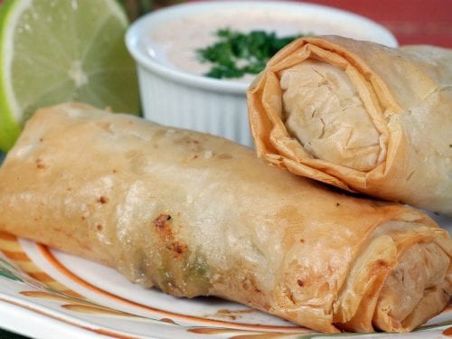 fried egg rolls with a dipping sauce and half a lime in the background