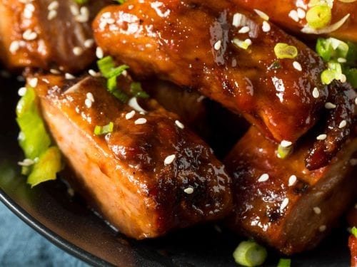 closeup bbq ribs garnished with chopped green onions and sesame seeds