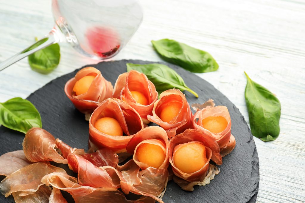 honeydew melon are wrapped in prosciutto and fresh mint