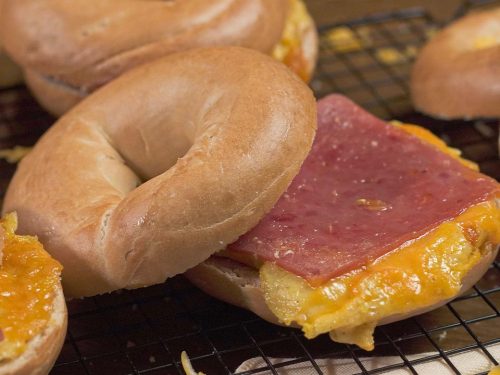 McDonald’s-Inspired Breakfast Sandwich Recipe, Bagel cut in half with cheese, ham, and scrambled eggs in the middle to form a sandwich