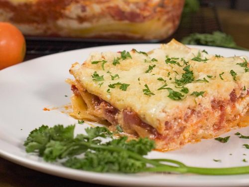 Olive Garden’s Lasagna Classico Recipe, Slice of lasagna topped with parsley and served on white plate