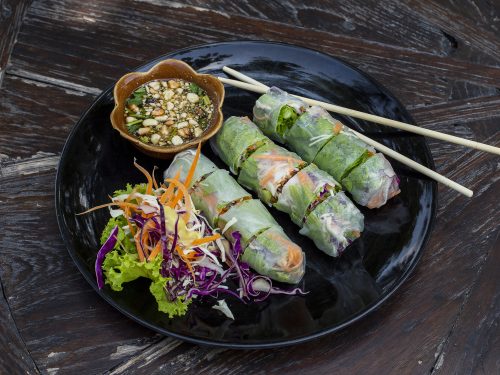 fresh vietnamese spring rolls, veggies, and nuoc cham on a black plate