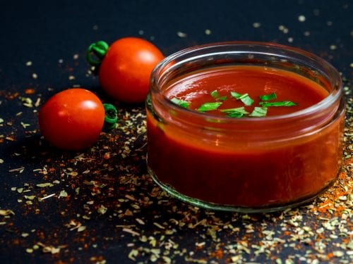 Arby's Sauce homemade ketchup-roast beef sauce on a storage jar, fresh tomatoes in the background