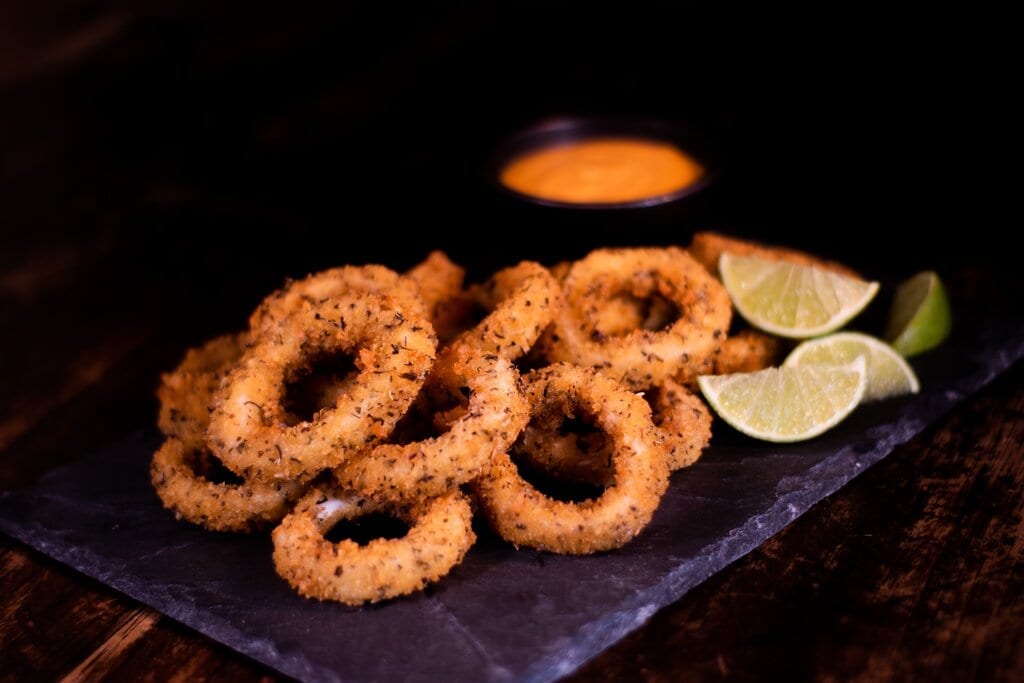 Calamari Fritti Recipe, fried calamari rings on a plate with lemon wedges and dip