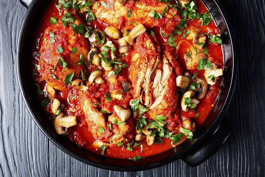 a top view of chicken cacciatore in a black dutch oven