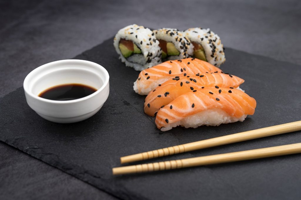 Pieces of nigiri sushi and maki with a soy sauce dip on the side